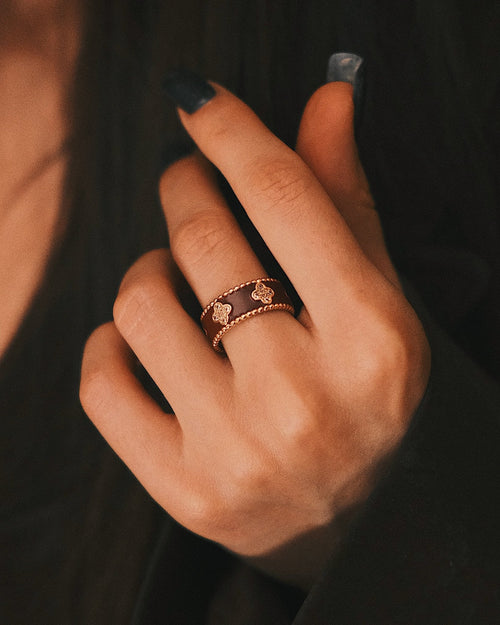 Burgundy Quatrefoil Band on the finger, a gold-tone band with burgundy quatrefoils, dark sleeve